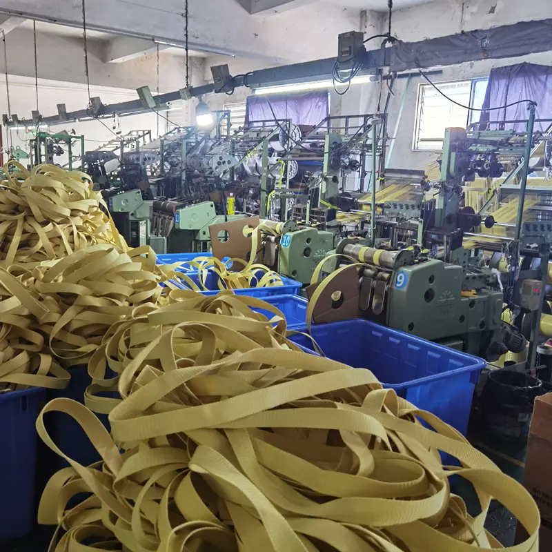 Rollos de cinta amarilla de aramida KEVLAR® en producción, conocida por sus propiedades ignífugas y antibalas.